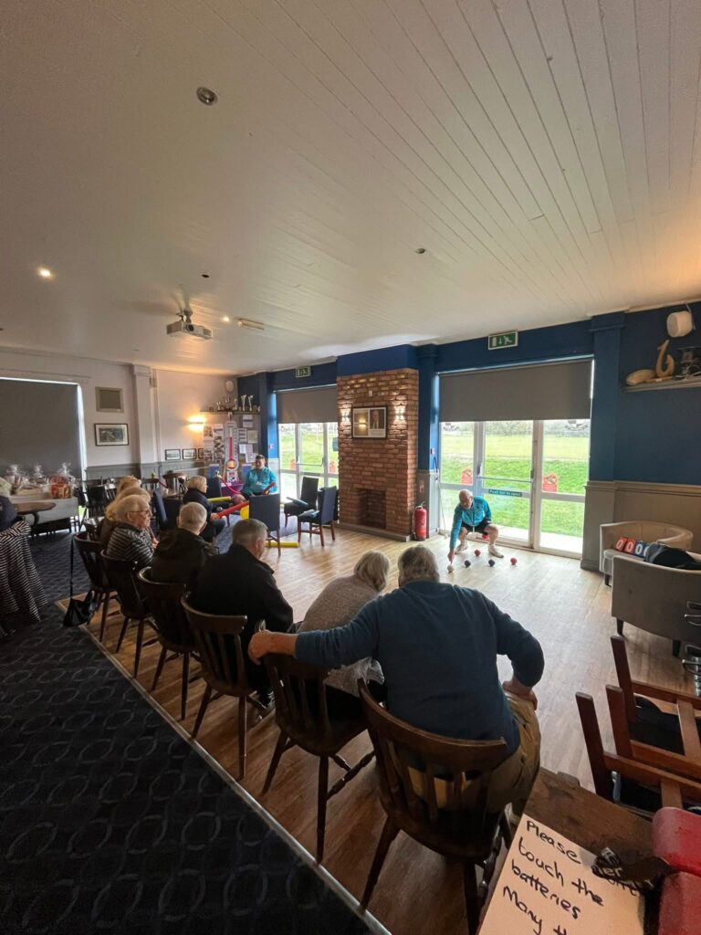 Seniors playing indoor bowls at community centre.